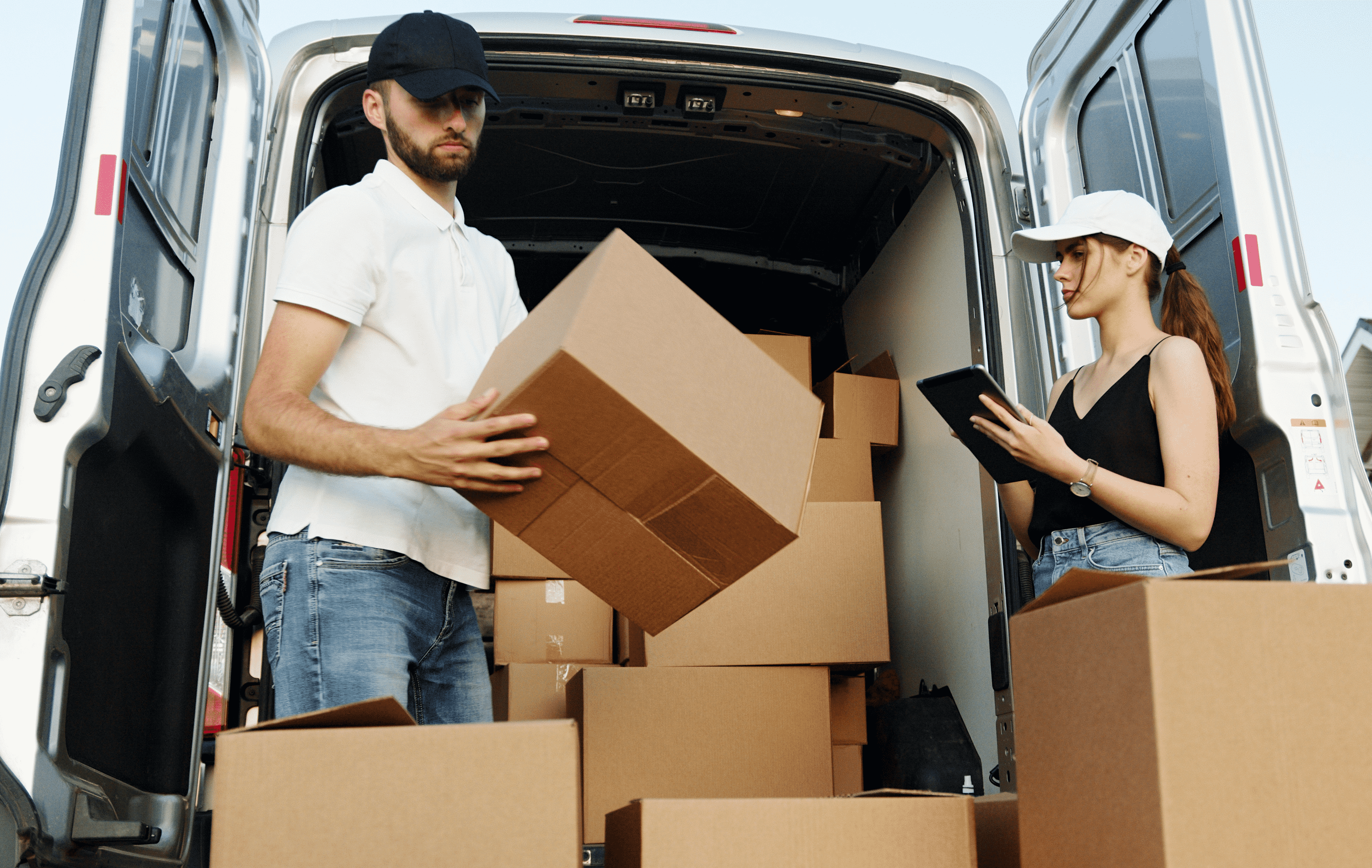 a man and woman loading a van with shipping packages