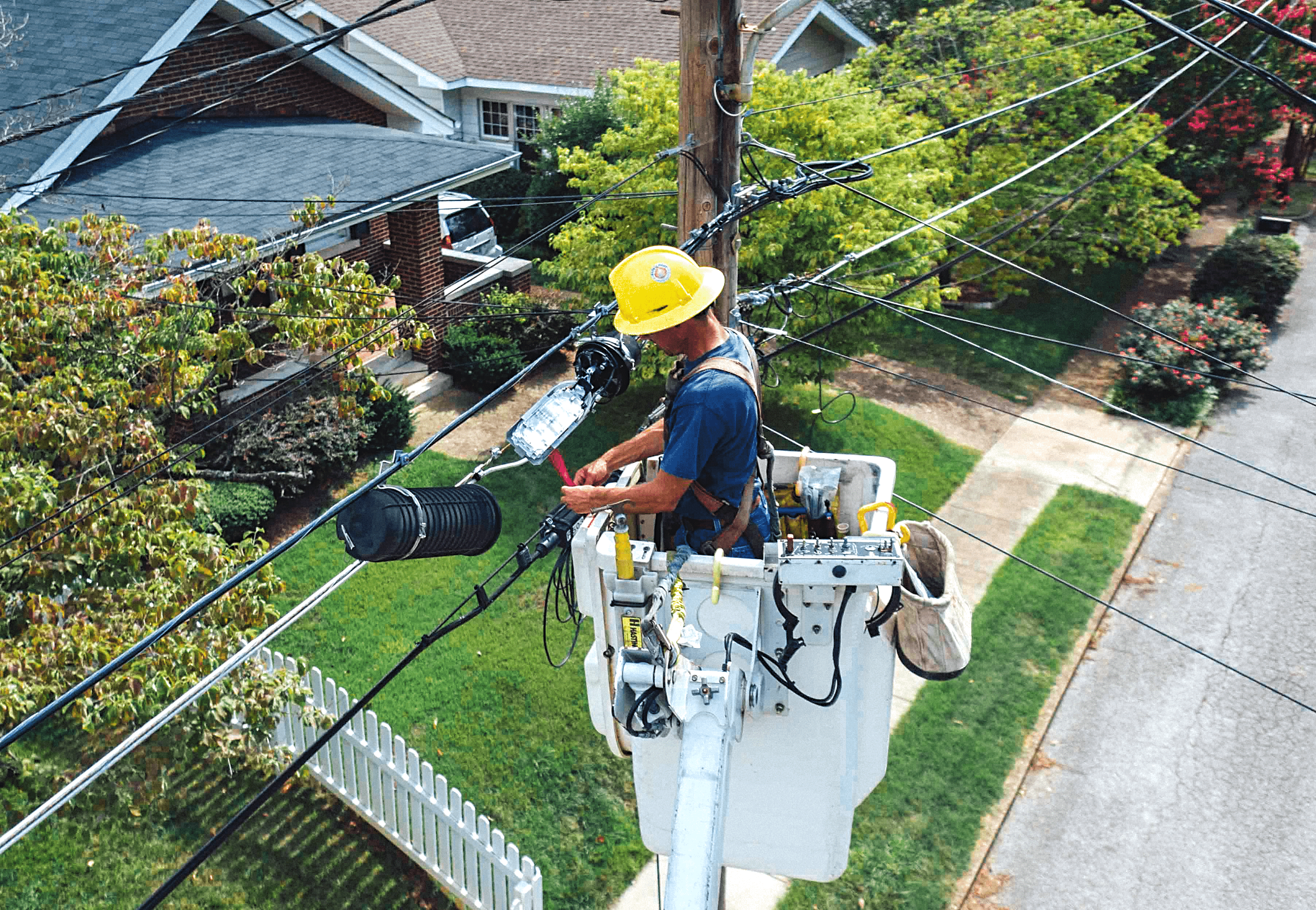 utility worker in hard hat working on power lines while standing in a cherry-picker